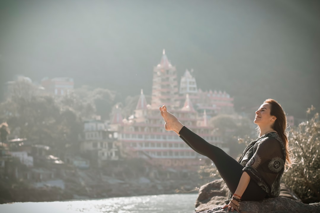 Offerings a-woman-sitting-on-top-of-a-rock-next-to-a-river-luasfx0lcjo