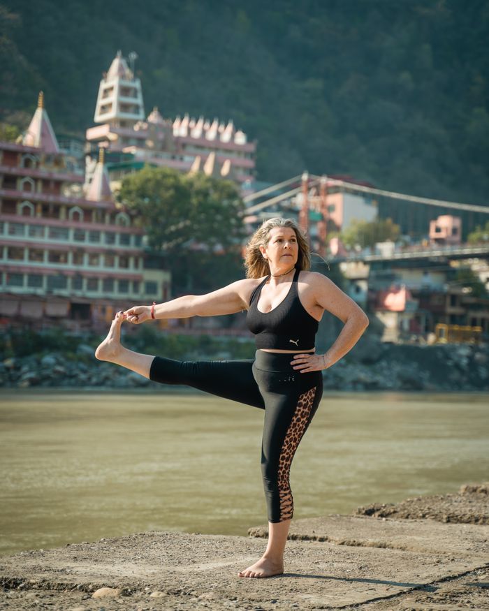 The Art of Drawing Readers In: Your attractive post title goes here Middle-aged woman performing yoga by a river in India, showcasing wellness and tranquility.