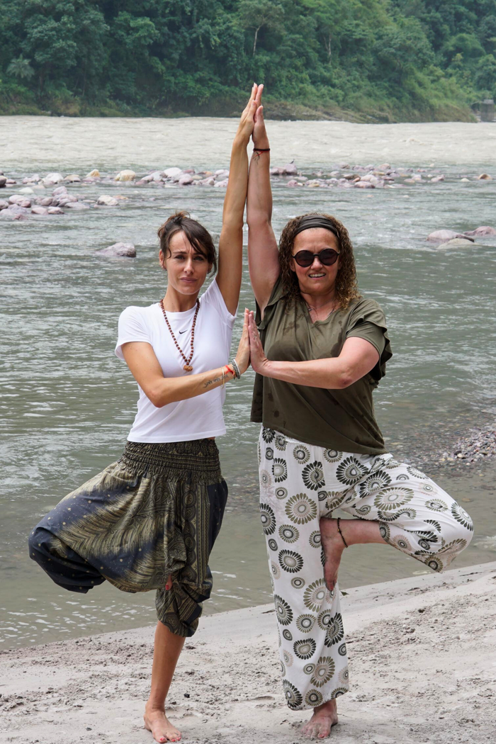 Crafting Captivating Headlines: Your awesome post title goes here Two women practicing yoga poses by the river in Rishikesh, India, embracing wellness and nature.